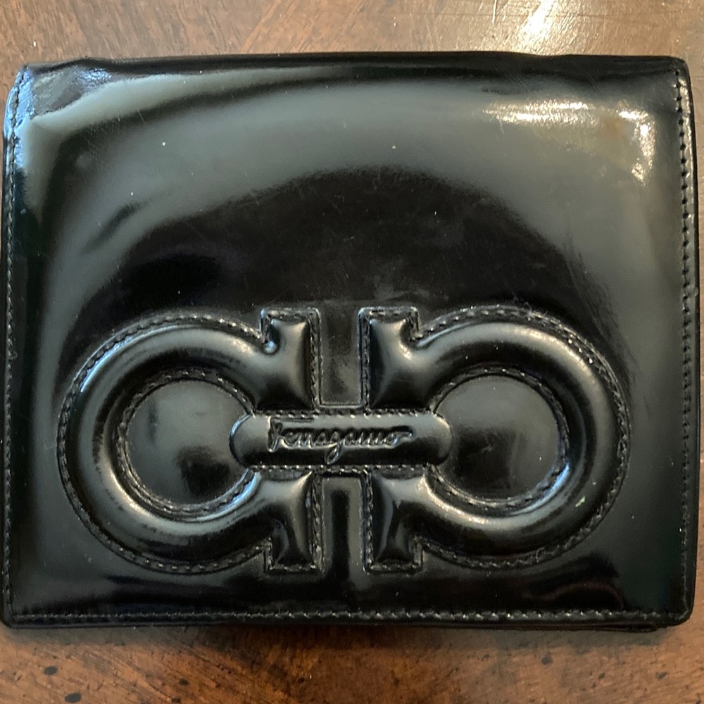 Ferragamo black patent bifold wallet featuring the iconic Double Gancini logo.
